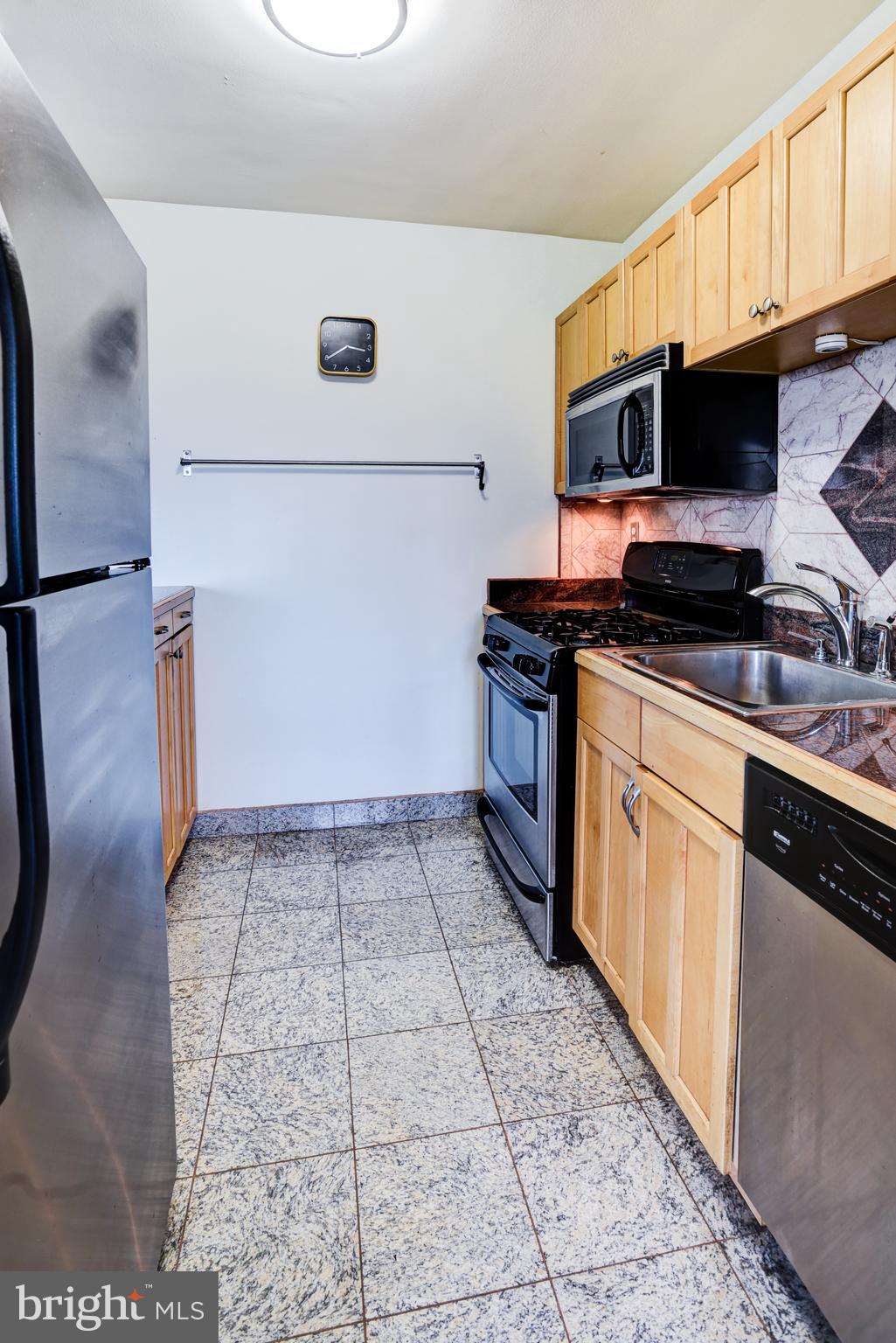 4201 Cathedral Avenue Northwest, Unit 1411E Washington, DC 20016 - Photo 28 of 66 a kitchen with stainless steel appliances granite countertop a stove a sink and a microwave