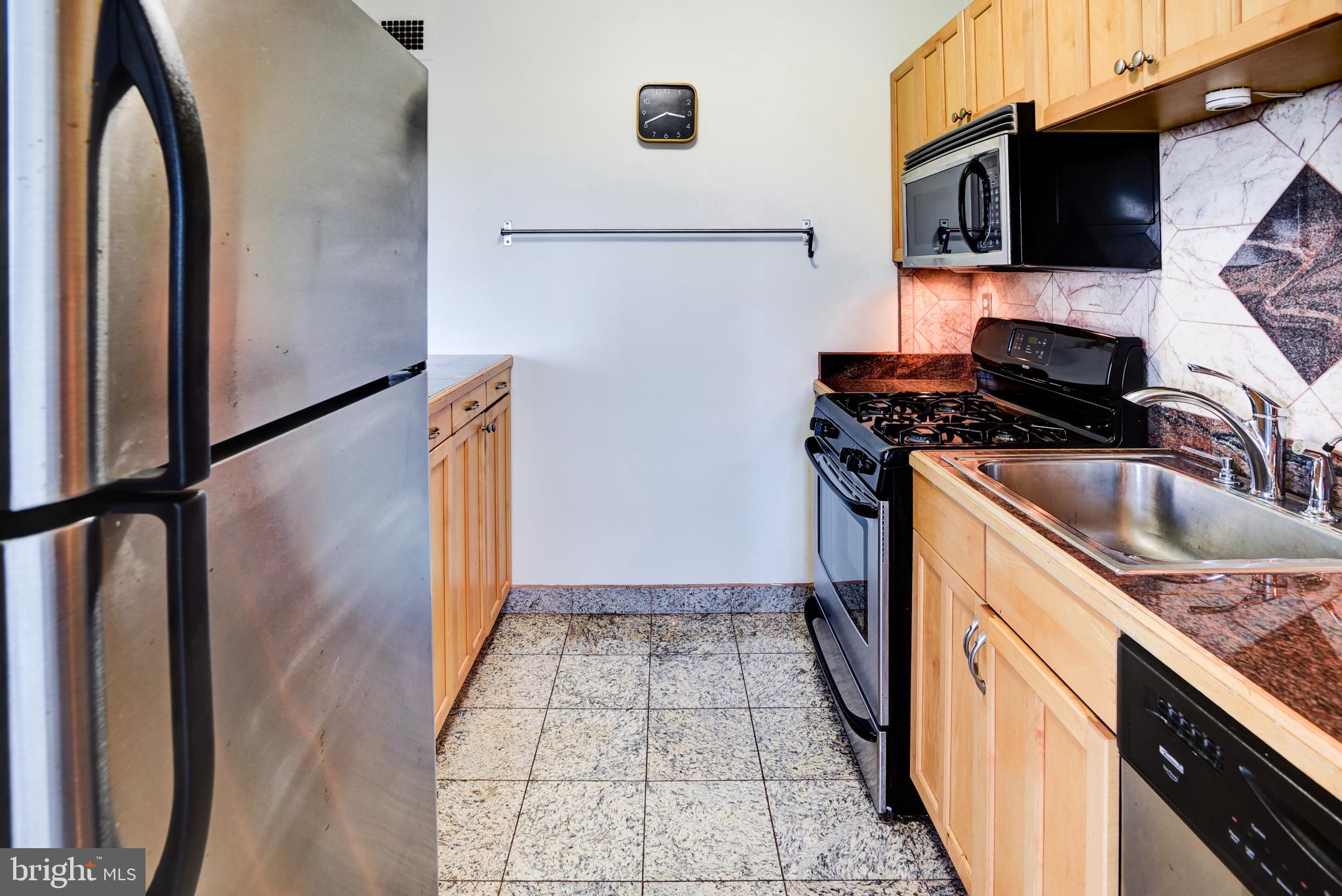 4201 Cathedral Avenue Northwest, Unit 1411E Washington, DC 20016 - Photo 29 of 66 a kitchen with stainless steel appliances granite countertop a refrigerator and a stove top oven