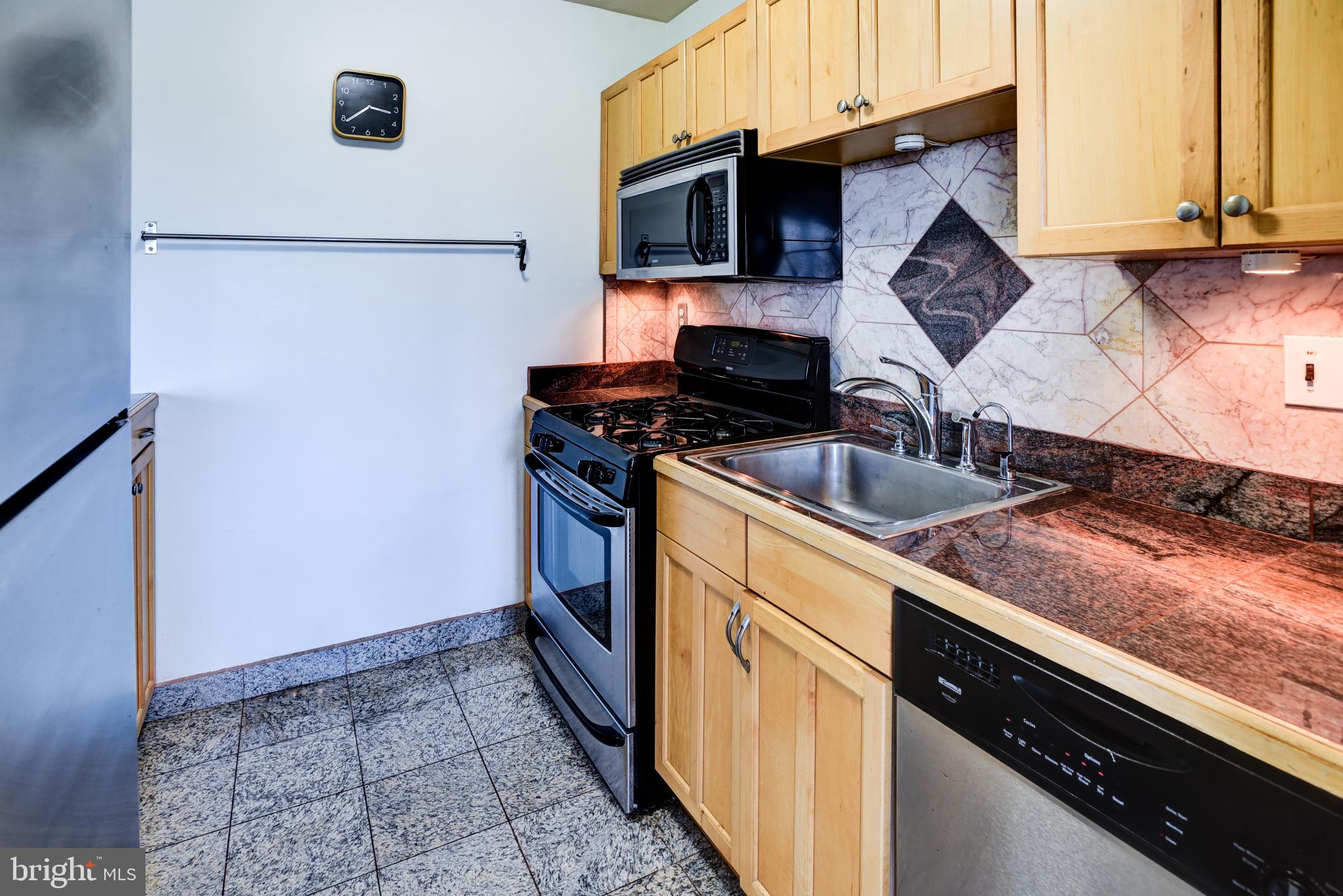 4201 Cathedral Avenue Northwest, Unit 1411E Washington, DC 20016 - Photo 30 of 66 a kitchen with stainless steel appliances granite countertop a sink stove and refrigerator