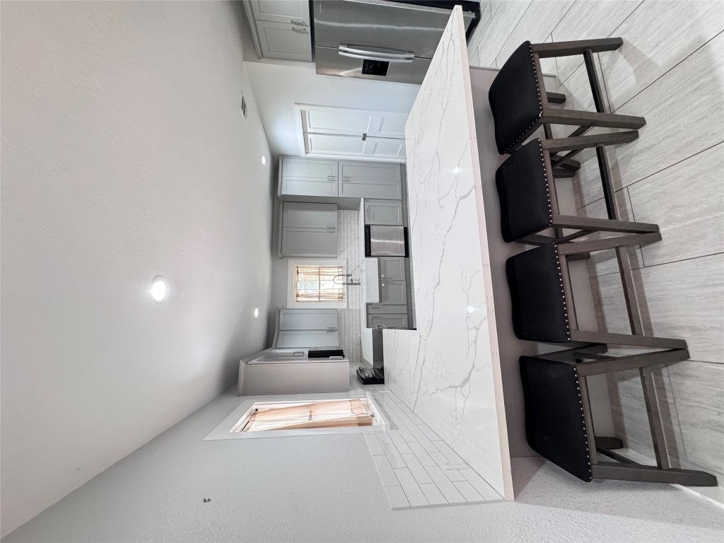 939 Knape Road La Grange, TX 78945 - Photo 14 of 37 Kitchen with gray cabinets, a breakfast bar, a peninsula, decorative backsplash, and a textured wall
