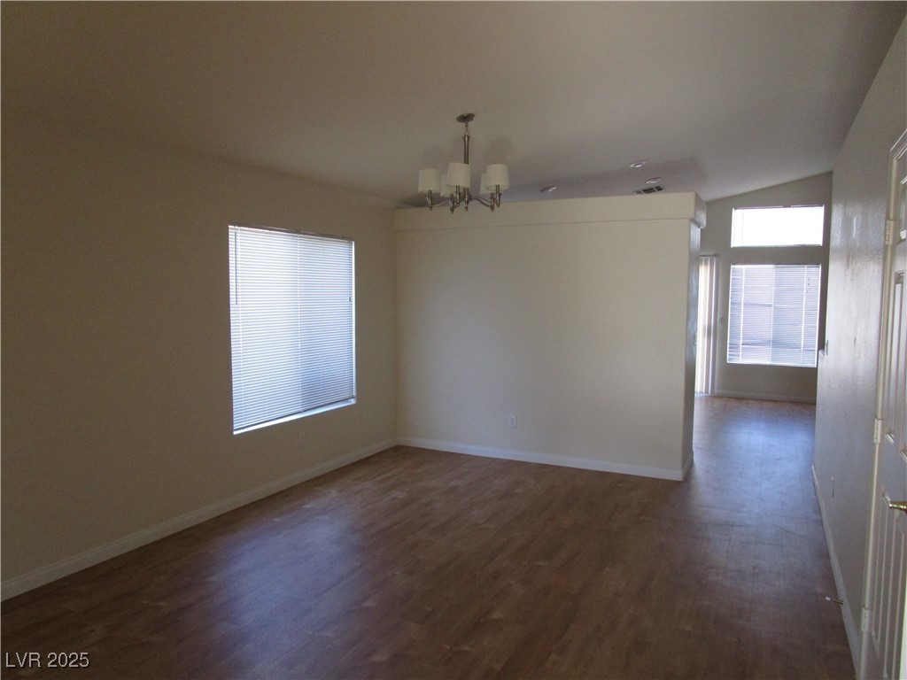 1966 Windfall Avenue Henderson, NV 89012 - Photo 2 of 13 Unfurnished dining area with dark wood finished floors, lofted ceiling, and a chandelier