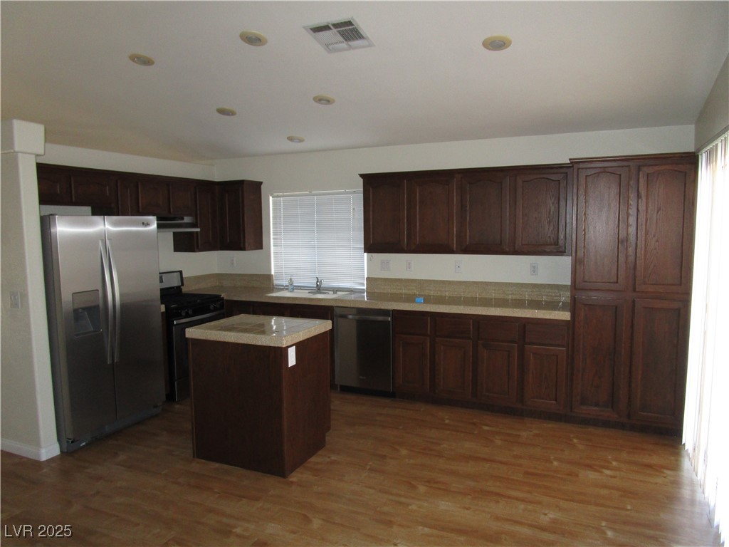 1966 Windfall Avenue Henderson, NV 89012 - Photo 3 of 13 Kitchen with stainless steel appliances, light wood-style floors, a kitchen island, light countertops, and dark brown cabinetry