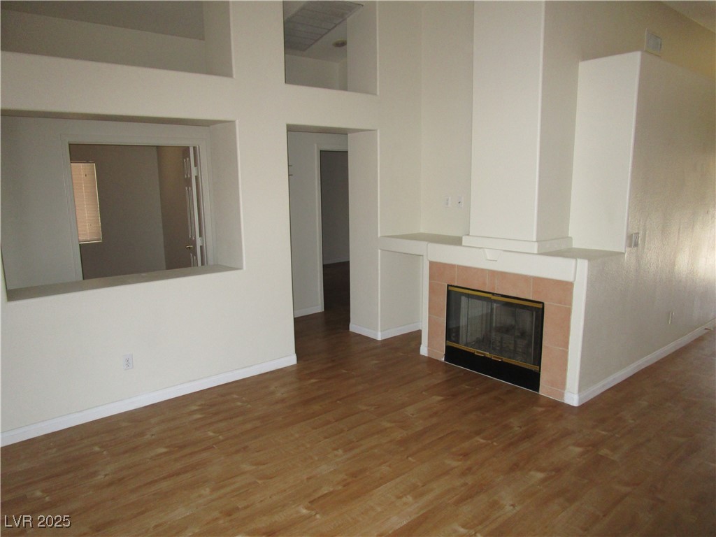 1966 Windfall Avenue Henderson, NV 89012 - Photo 6 of 13 Unfurnished living room with a high ceiling, a tiled fireplace, and wood finished floors