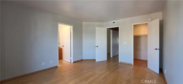 a view of an empty room with wooden floor and closet