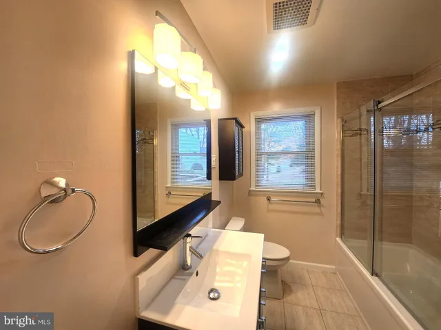a bathroom with a granite countertop sink a toilet and shower