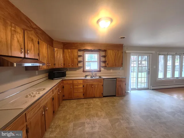 a open kitchen with granite countertop a stove top oven a sink dishwasher and cabinets with wooden floor