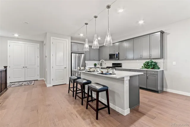 a kitchen with kitchen island stainless steel appliances a table chairs sink and cabinets
