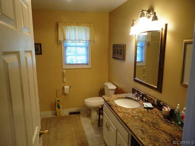 1585 Copper Line Road Bumpass, VA 23024 - Photo 13 of 24 a bathroom with a granite countertop sink toilet and mirror