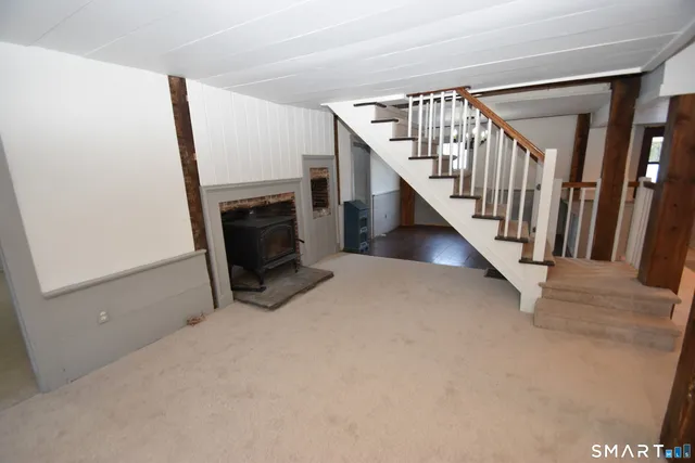 a view of an empty room with fireplace stairs and a window