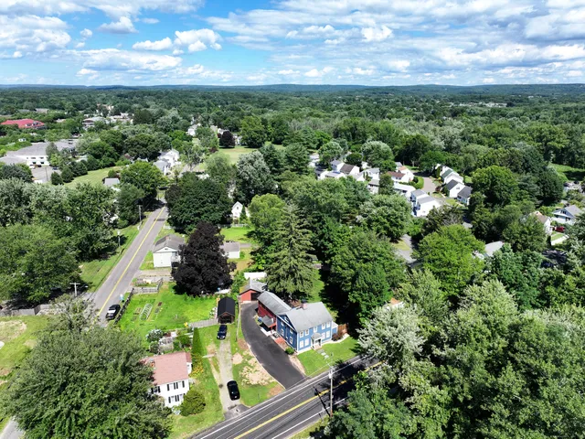 an aerial view of a residential houses with outdoor space and trees