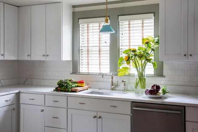 a kitchen with stainless steel appliances white cabinets a window and a sink