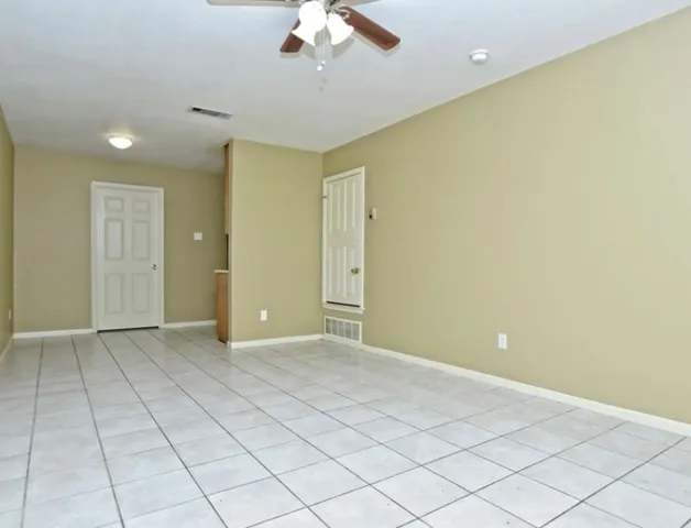 an empty room with a ceiling fan and carpet