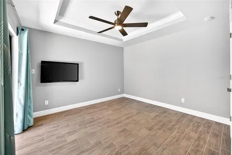 an empty room with wooden floor and a ceiling fan