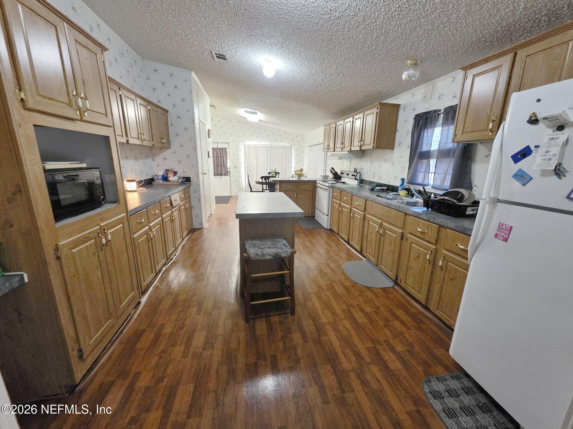 44680 Artesian Boulevard Callahan, FL 32011 - Photo 18 of 47 a kitchen with granite countertop a refrigerator a stove top oven a sink dishwasher and wooden cabinets with wooden floor