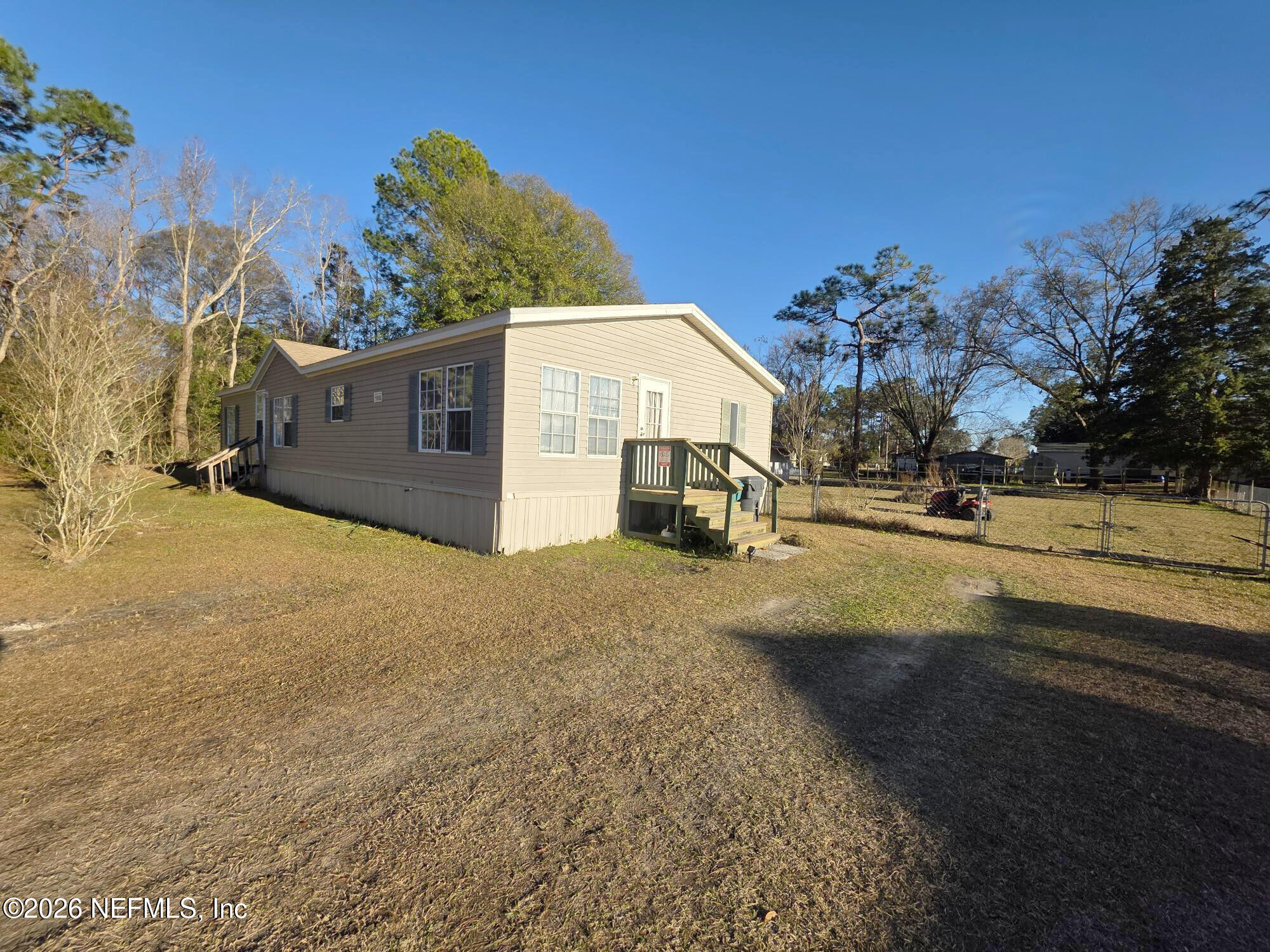 44680 Artesian Boulevard Callahan, FL 32011 - Photo 4 of 47 a view of a white house with a yard and a wooden fence