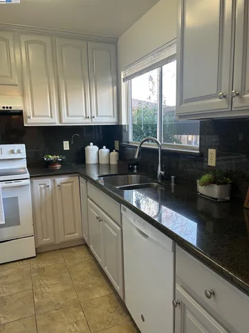 a kitchen with granite countertop white cabinets and white appliances