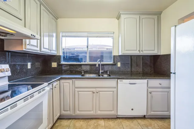 a kitchen with granite countertop white cabinets and white appliances