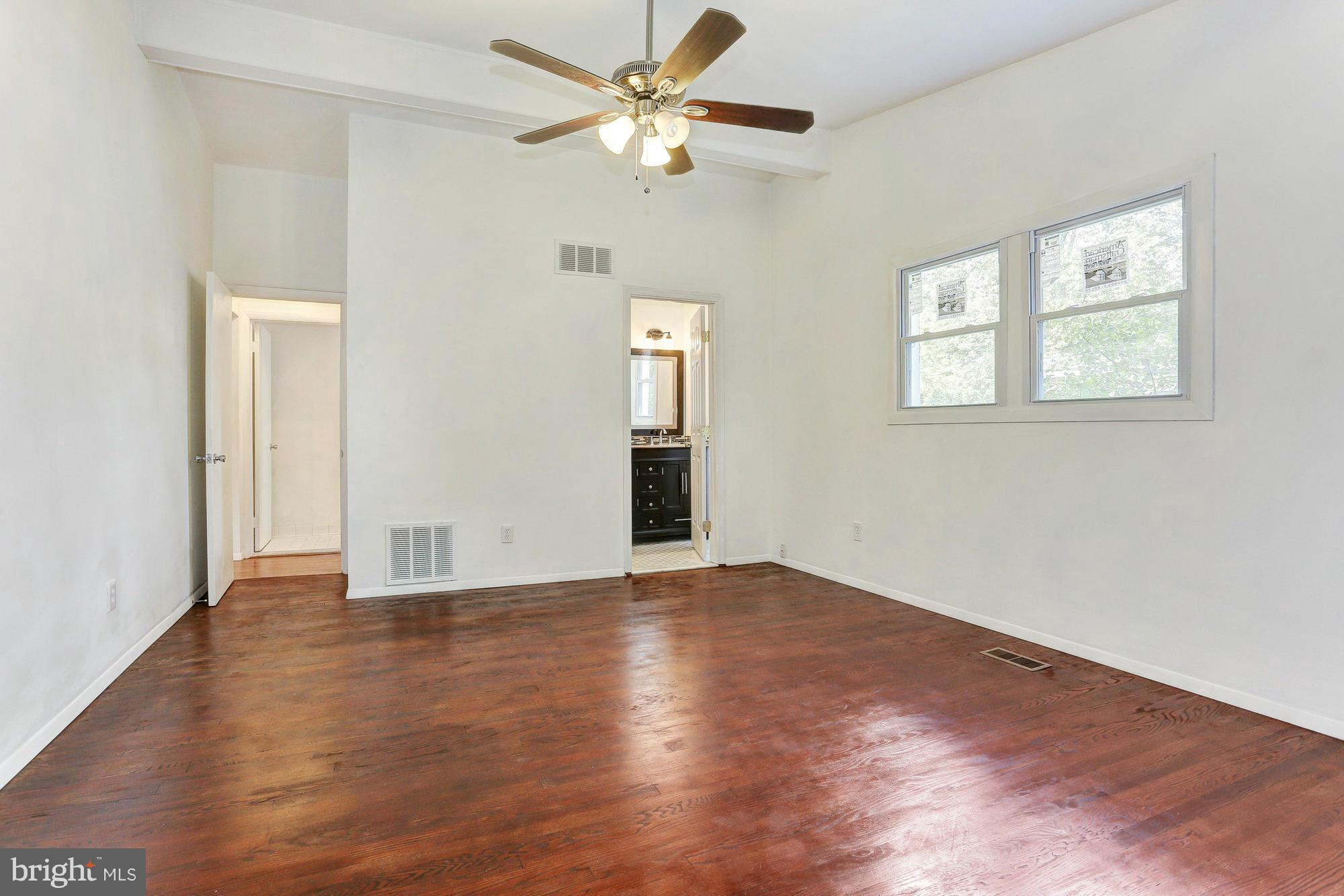 9405 Tulsemere Road Randallstown, MD 21133 - Photo 11 of 26 an empty room with wooden floor chandelier fan and windows