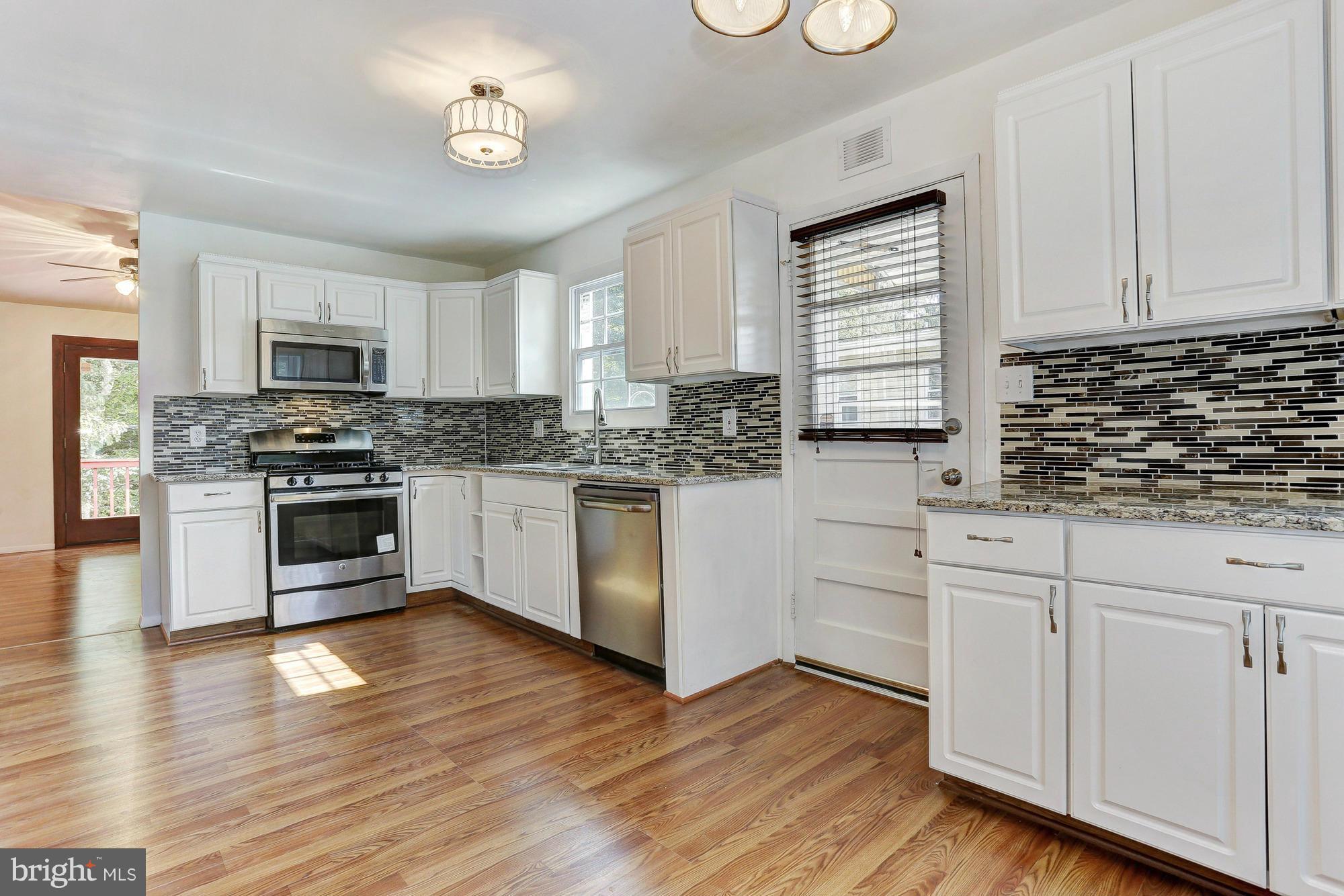 9405 Tulsemere Road Randallstown, MD 21133 - Photo 5 of 26 a kitchen with white cabinets stainless steel appliances and wooden floor