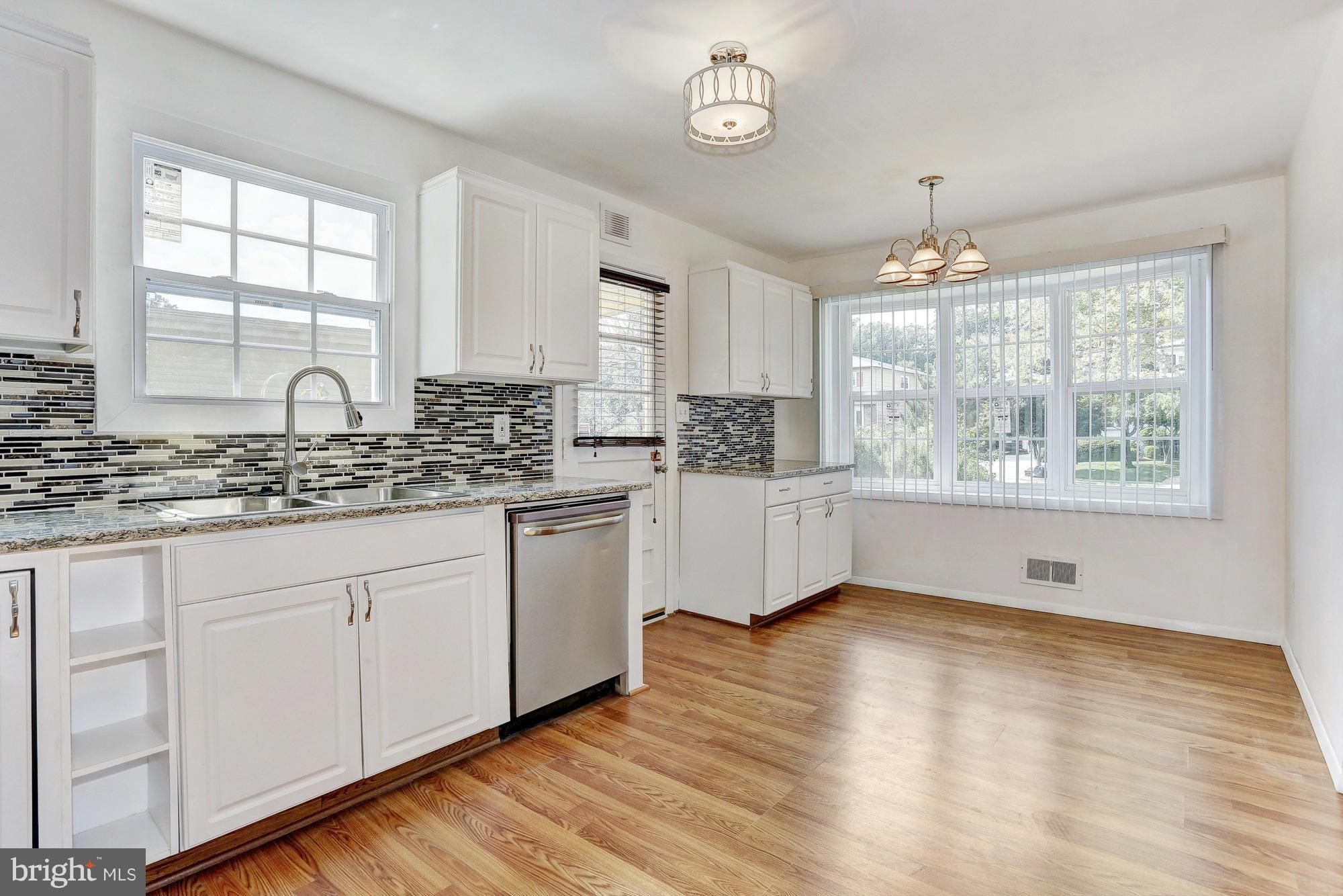 9405 Tulsemere Road Randallstown, MD 21133 - Photo 8 of 26 a kitchen with stainless steel appliances granite countertop white cabinets a sink a window and wooden floor