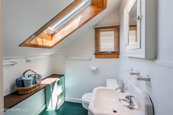 a bathroom with a sink a toilet and a window