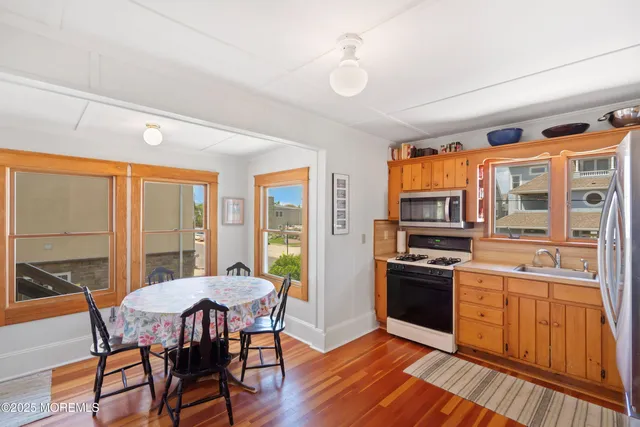 a view of a dining room with furniture large windows a chandelier and wooden floor