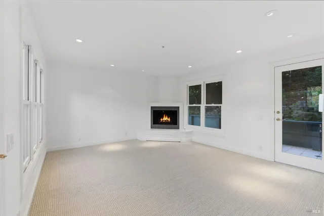 an empty room with a fireplace and windows