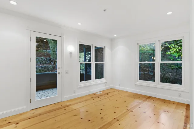 a view of an empty room with a window and wooden floor