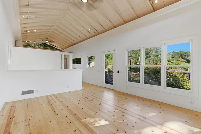 a view of a big room with wooden floor and windows