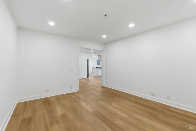 a view of an empty room with wooden floor and windows