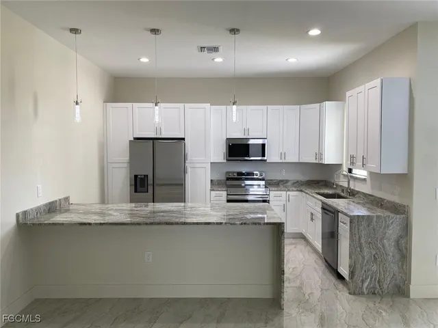 a large kitchen with stainless steel appliances granite countertop a stove a sink and a microwave