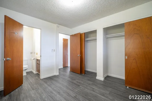 a view of an empty room with wooden floor and closet