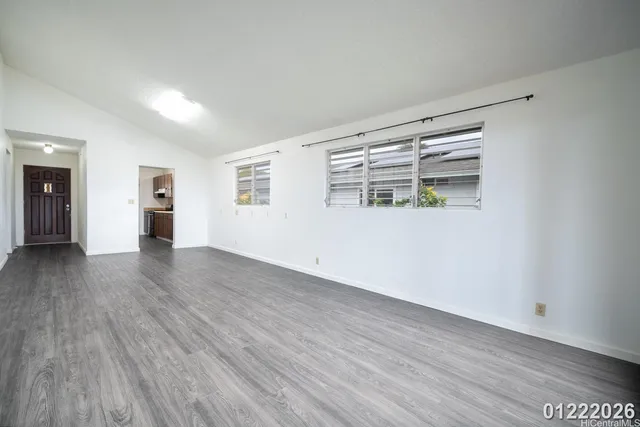 a view of empty room with wooden floor and window