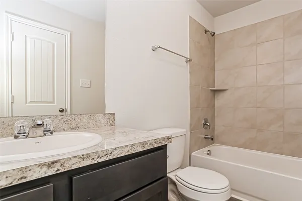 a bathroom with a granite countertop sink a toilet and shower