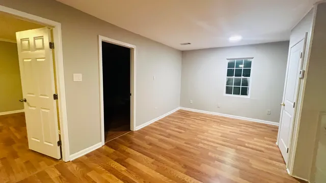 a view of an empty room with wooden floor and a window