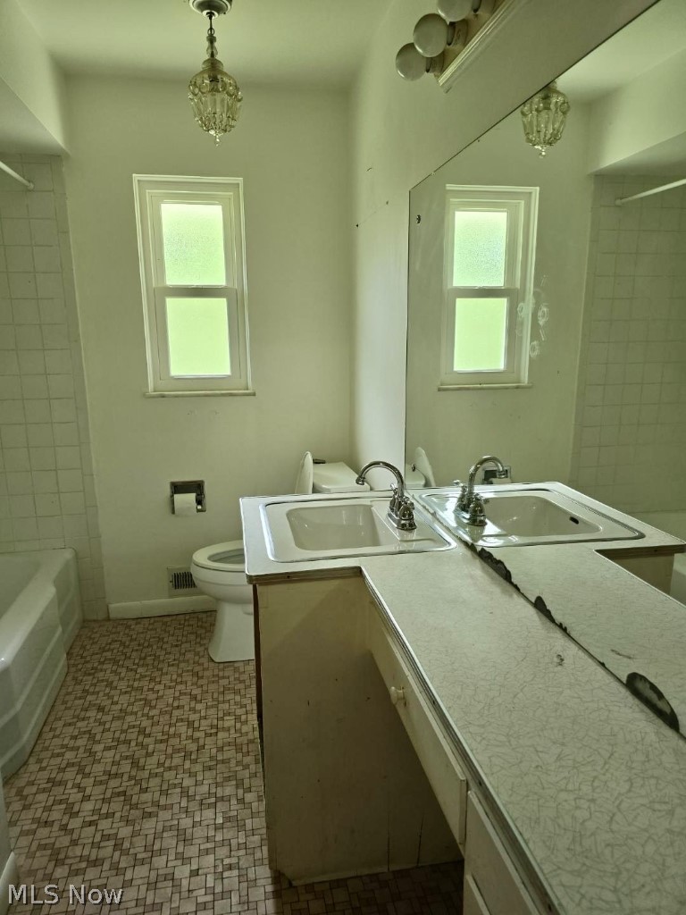 7735 Ragall Parkway Cleveland, OH 44130 - Photo 21 of 32 Full bathroom featuring a chandelier, tiled shower / bath, toilet, vanity, and tile patterned floors