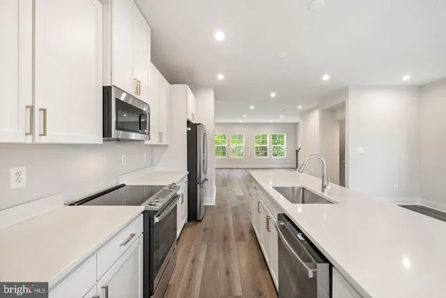 a kitchen with a sink a counter top space stainless steel appliances and cabinets