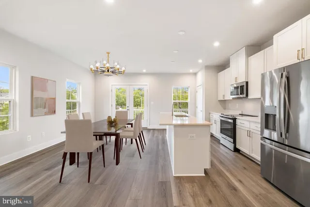 a kitchen with stainless steel appliances granite countertop a stove top oven a sink dishwasher a dining table and chairs with wooden floor