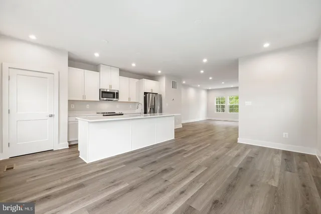 a view of kitchen with granite countertop refrigerator oven sink and white cabinets with wooden floor