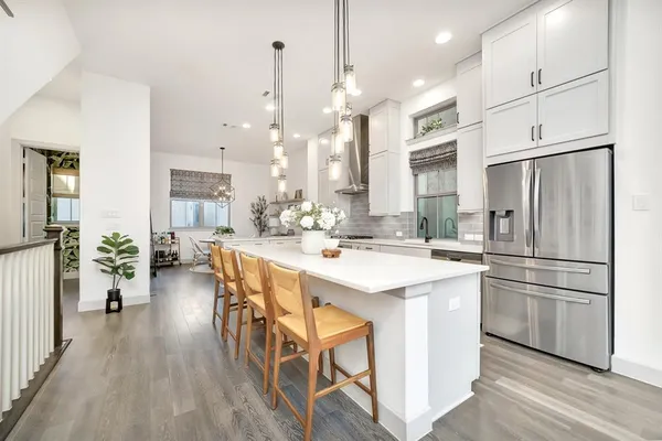 a kitchen with stainless steel appliances a refrigerator a stove a sink dishwasher and a dining table with wooden floor