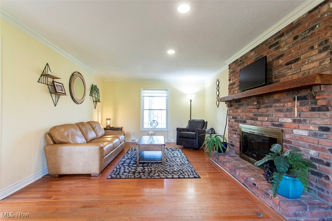 4041 Huffman Road Medina, OH 44256 - Photo 12 of 40 Living room featuring light wood-type flooring, a brick fireplace, and ornamental molding