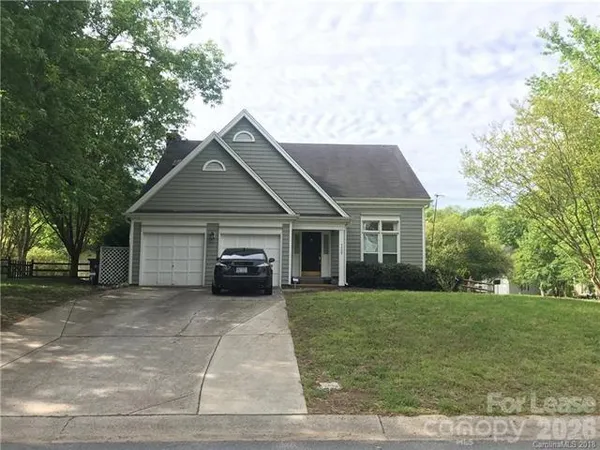 a front view of a house with a garden and trees