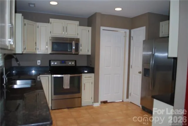 a kitchen with stainless steel appliances granite countertop a refrigerator and a stove top oven