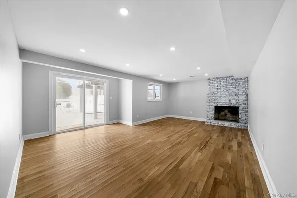 a view of empty room with wooden floor and fireplace