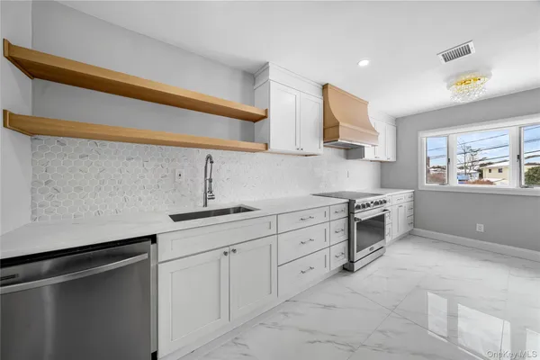 a kitchen with stainless steel appliances a sink dishwasher stove and white cabinets