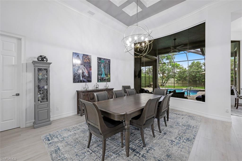 7235 Mill Run Road Naples, FL 34109 - Photo 17 of 31 a dining room with furniture a chandelier and wooden floor