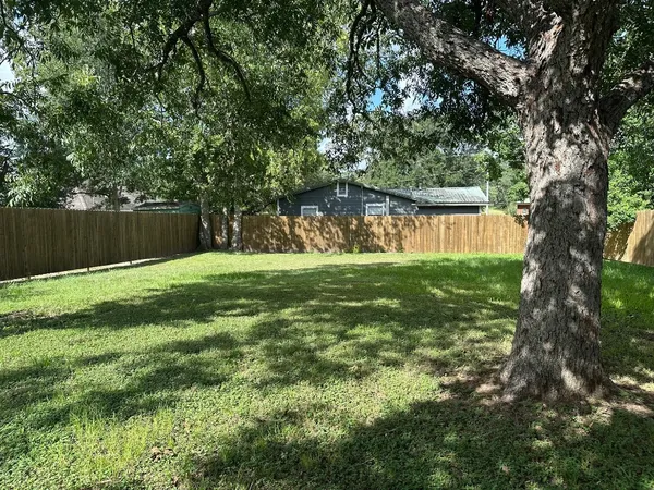 a backyard of a house with lots of plants and large tree