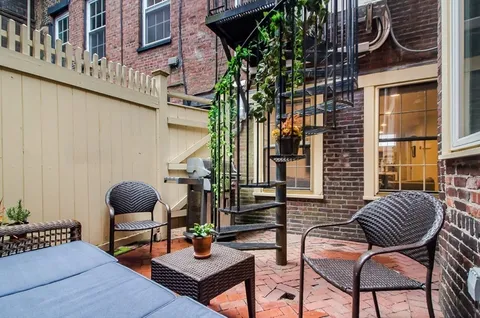 a view of a brick building with table and chairs and potted plants