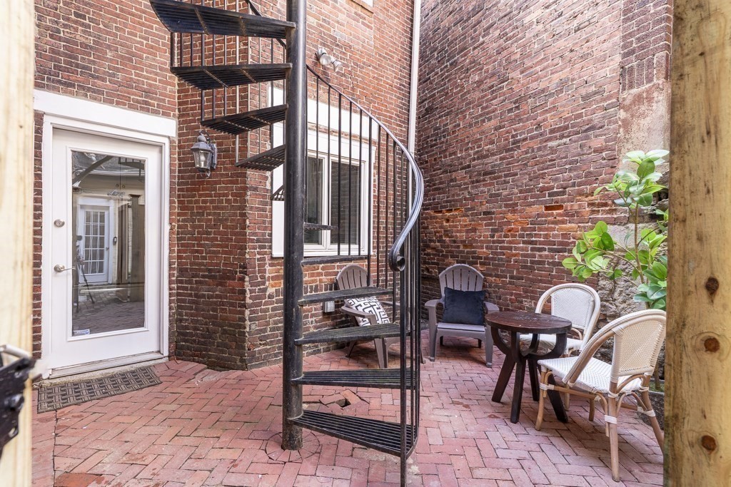18 Melrose Street, Unit 1 Boston, MA 02116 - Photo 20 of 24 a view of a brick building with table and chairs and potted plants
