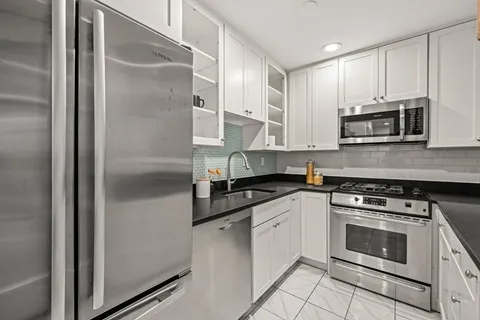 a kitchen with stainless steel appliances granite countertop a stove a refrigerator and a microwave